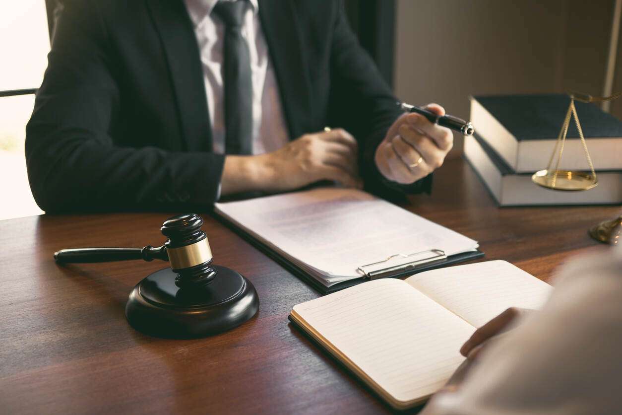 Long Beach Personal injury Lawyer personal injury lawyer wearing blak suite and discussing injury claim with client and lawyer gavel on the table .