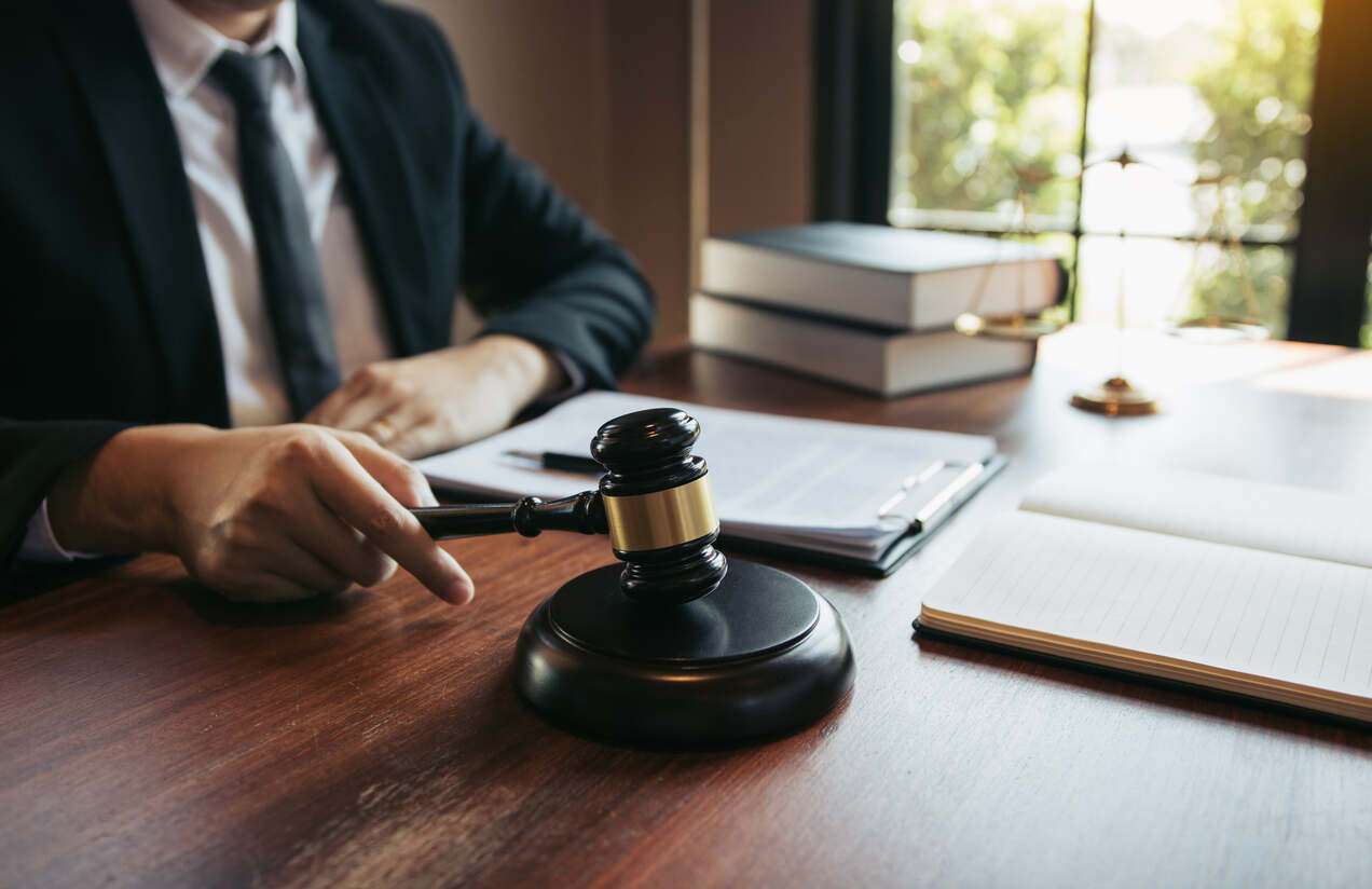A legal professional in a suit seated at a desk with a gavel and books, representing the services of a personal injury lawyer serving San Bernardino.