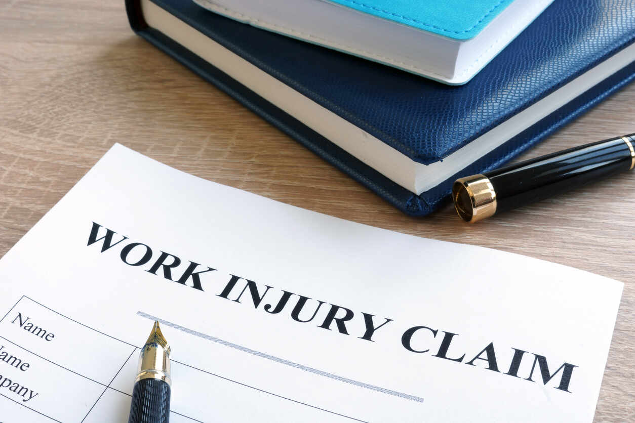 El Monte Worker compensation lawyer Work Injury Claim form with a pen and legal books, symbolizing workers' compensation.
