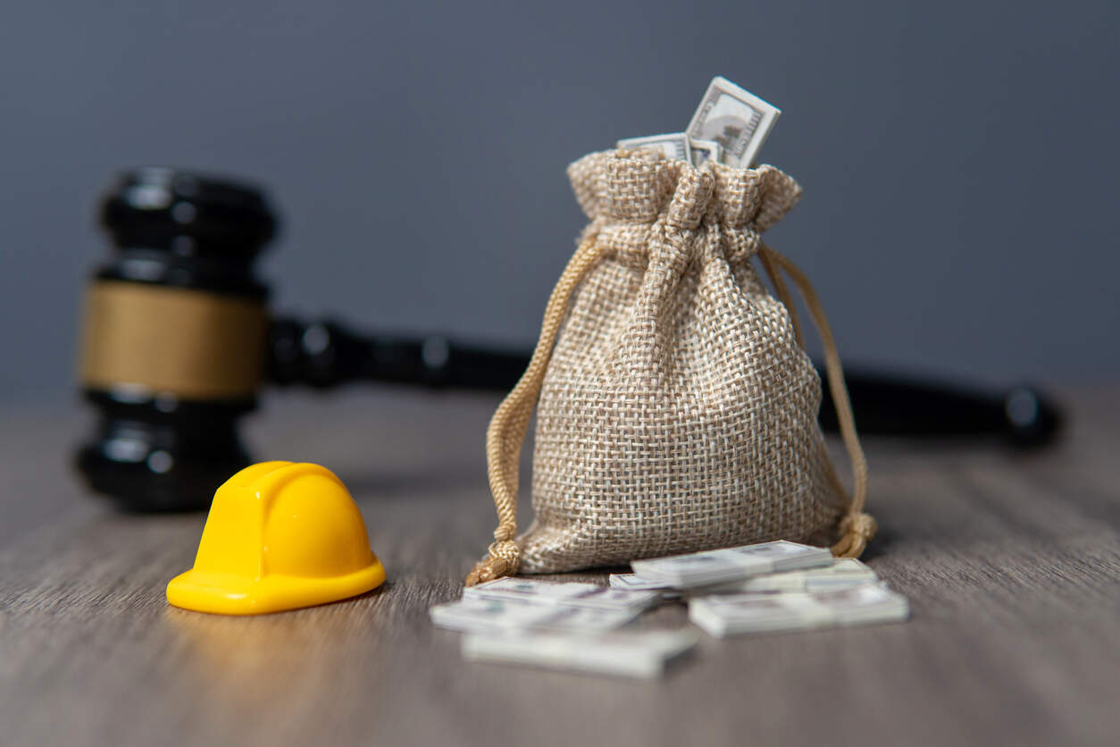 San Bernardino Workers Compensation lawyer Gavel, money bag, and hard hat, symbolizing workers' compensation claims in San Bernardino.