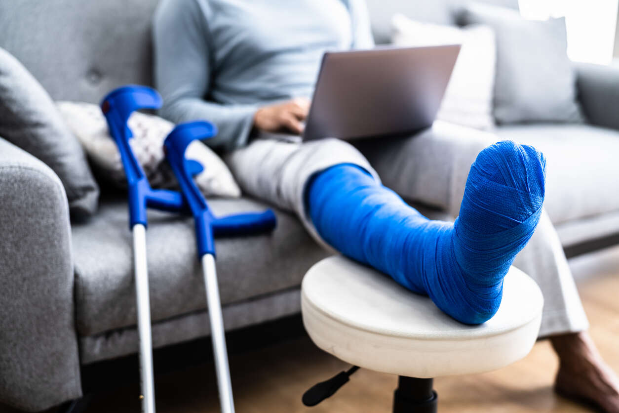 pasadena worker compensation lawyer Person with a leg cast and crutches using a laptop, symbolizing a worker's compensation claim.
