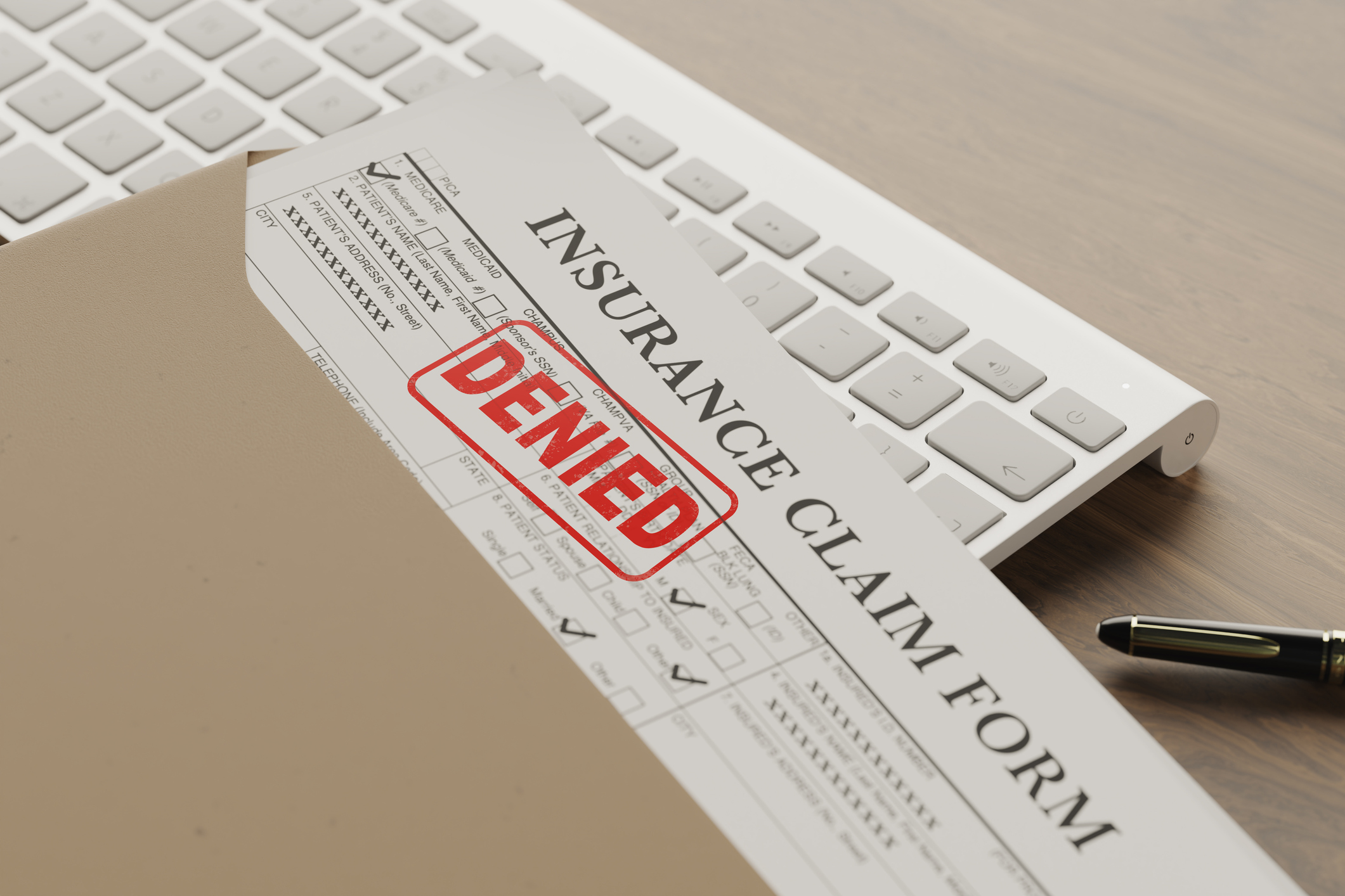 Formulario de solicitud de seguro médico denegado sobre la mesa. Formulario de reclamo de seguro con el sello de 'Denegado', que representa una situación en la que se deniega la compensación para trabajadores, mostrado sobre un escritorio con un teclado y un bolígrafo.